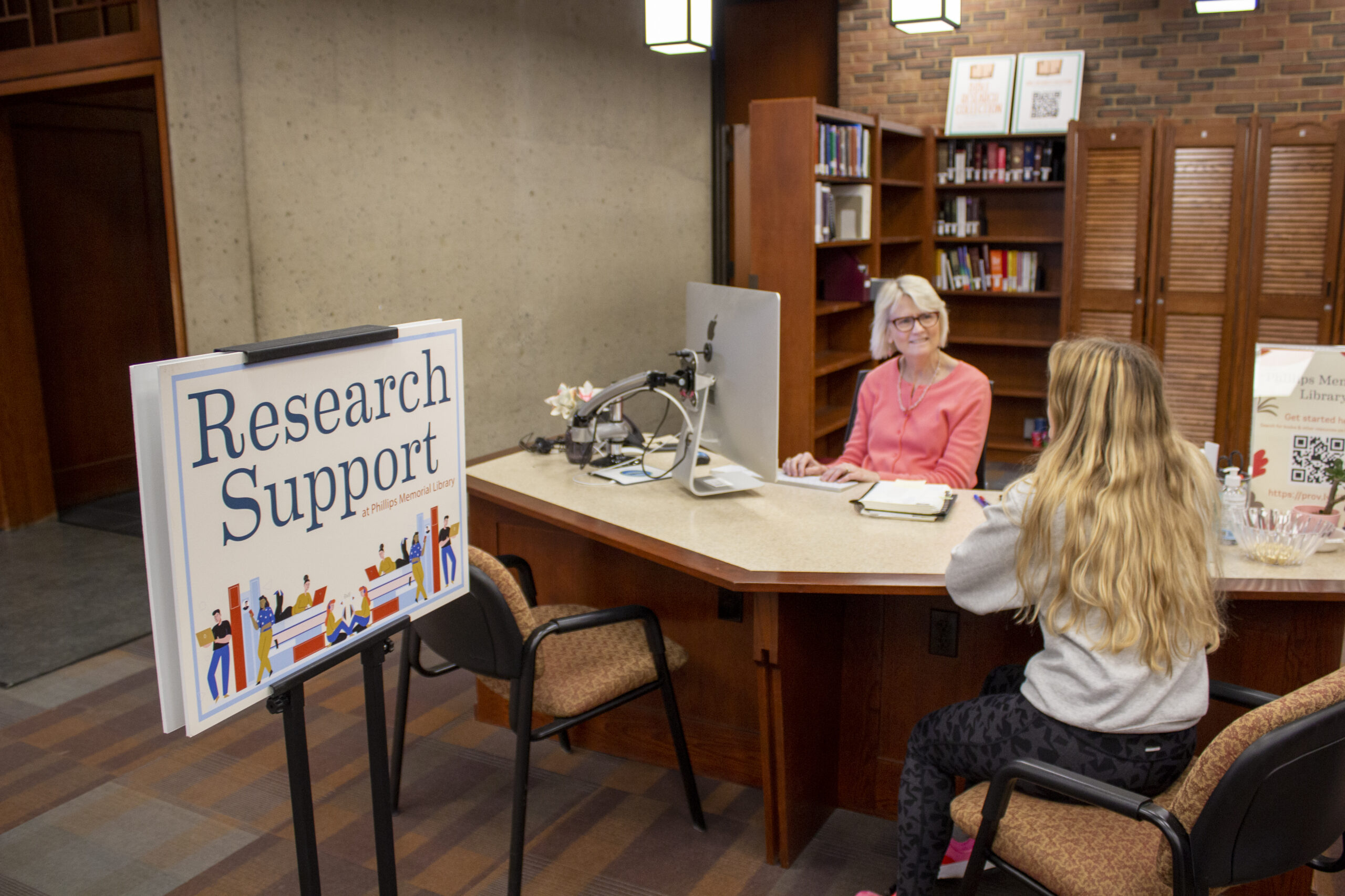 A librarian assisting a student a the Research Support desk.