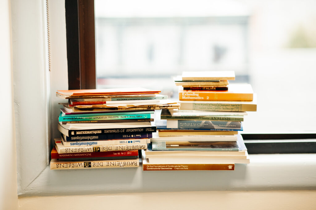 Two stacks of books on a windowsill.