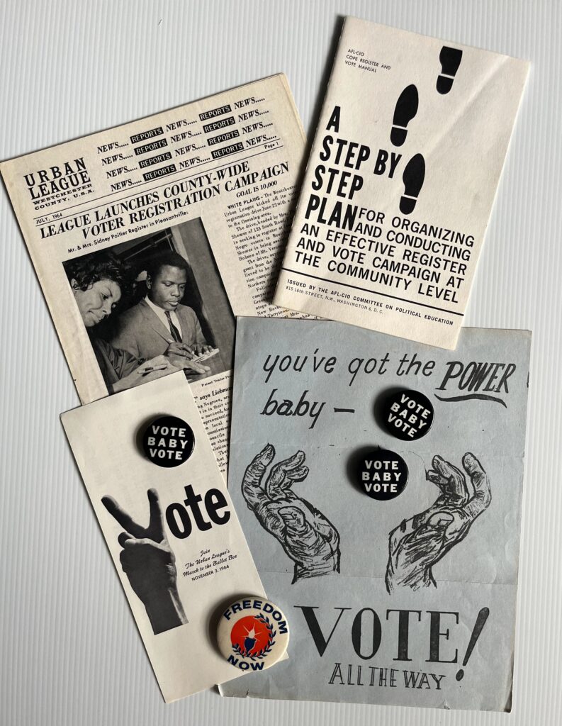 A collection of mid-1960s civil rights era voting materials, including pamphlets, buttons, and flyers. Items include: an Urban League newspaper announcing a voter registration campaign; a pamphlet titled A Step by Step Plan with footprints on the cover; a flyer with the words “you’ve got the POWER baby – VOTE all the way” illustrated with drawn hands; and a leaflet showing a raised hand making a peace sign next to the word “Vote.” Several campaign buttons are displayed, reading “Vote Baby Vote” and “Freedom Now.”